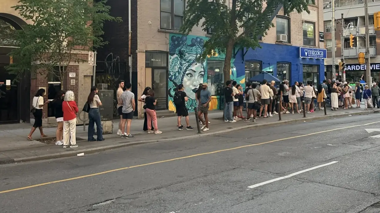 A long line of customers outside the blue Mizzica shopfront on John Street, by Queen Street West